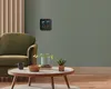 A living room scene with a chair, coffee table, and a weather station on the wall. Náhled obrázku produktu