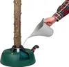 A person is watering a Christmas tree that is placed in a green tree stand. Náhľad obrázku produktu