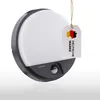A round, black and gray outdoor LED wall light with a motion sensor is shown against a white and light gray background. A tag with the German flag and the text 'DEUTSCHE MARKE' is attached to the light. Produktbild-Vorschau