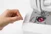 A hand is shown threading a sewing machine. Anteprima dell’immagine prodotto