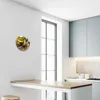 A round clock with an olive oil motif is displayed on a white wall in a modern kitchen setting. Produktbild-Vorschau