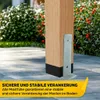 A wooden post with a metal bracket attached, set in a paved outdoor area with greenery and flowers in the background. A yellow banner with German text is at the bottom. Produktbild-Vorschau