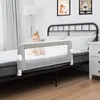 A baby is sitting on a bed with a bed rail installed. Anteprima dell’immagine prodotto
