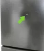A close-up of a stainless steel appliance with a green arrow pointing to a small blemish. Produktbild-Vorschau