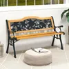 A garden bench with a decorative backrest is placed on a tiled patio next to a potted plant and a small ottoman. Produktbild-Vorschau