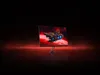 A gaming monitor displaying a spaceship in space, set against a dark, red-lit background. Produktbild-Vorschau