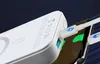 A close-up shot of a white power bank charging a smartphone. Podgląd zdjęcia produktu