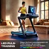A woman is running on a treadmill in a modern living room. Produktbild-Vorschau