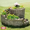 A spiral-shaped gabion planter filled with various plants and flowers, set in a grassy outdoor environment. Produktbild-Vorschau