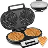 A waffle maker is shown open, with two heart-shaped waffles cooked on the bottom plate and the empty molds on the top plate. A single heart-shaped waffle is also shown next to the waffle maker. Produktbild-Vorschau
