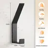 A black metal hook with water droplets on its surface, mounted on a textured white wall. Produktbild-Vorschau