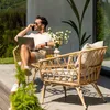 A man is sitting on a patio, working on his laptop and talking on his phone, with a set of outdoor furniture around him. Náhled obrázku produktu