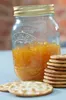 A jar of orange jam with crackers. Voir les images du produit