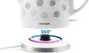 Close-up of a white electric kettle with a floral pattern, sitting on its charging base. Arrows indicate 360-degree rotation. Náhled obrázku produktu