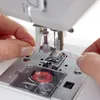 A close-up shot of a person's hands threading a sewing machine. Produktbild-Vorschau