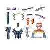 A collection of toy train track pieces and accessories, including trains, a trophy, track sections, a race arch, and a mountain-themed play structure. Náhľad obrázku produktu