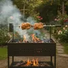 Two chickens are roasting on a rotisserie over a charcoal grill in a garden setting with roses in bloom. Náhľad obrázku produktu