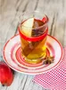 A hot beverage in a glass on a saucer, with an apple and spices. Náhled obrázku produktu