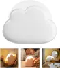 A collage of images showing a cloud-shaped LED night light in different contexts, including being held in hands, placed near a sleeping child, and on a shelf. Produktbild-Vorschau