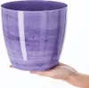 A hand holding a purple marble-patterned plant pot. Podgląd zdjęcia produktu