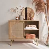 A wooden sideboard with a rattan door, decorated with various home decor items. Anteprima dell’immagine prodotto