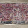 A close-up, angled view of a rug with a distressed, vintage-inspired pattern. Produktbild-Vorschau