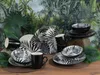 A collection of black and white patterned tableware arranged on a wooden surface with a tropical jungle wallpaper in the background. Náhľad obrázku produktu