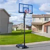 A portable basketball hoop is set up on a paved driveway in front of a residential house. Produktbild-Vorschau