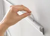 A hand is shown applying a strip of tape to a white decorative molding attached to a wall. Produktbild-Vorschau