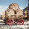 A wooden model of a wagon loaded with barrels, set against a blurred background of a town. Produktbild-Vorschau