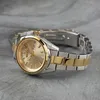 A close-up, angled shot of a two-tone gold and silver watch on a textured gray surface. Anteprima dell’immagine prodotto