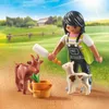 A Playmobil figure feeding baby goats in a grassy field with a barn in the background. Produktbild-Vorschau