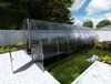 A greenhouse in a backyard setting with a table and chairs nearby. Podgląd zdjęcia produktu