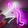 A neon unicorn light is displayed on a wall, with books and small star decorations around it. Náhled obrázku produktu