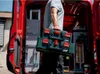 A person is carrying toolboxes out of a red van. Produktbild-Vorschau