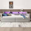 A gray upholstered daybed with built-in storage drawers and a headboard featuring LED lighting and charging ports. Produktbild-Vorschau