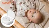 A baby lying on a patterned blanket, with a small white device in the foreground. Voir les images du produit