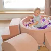 A young child is playing in a ball pit with soft play elements. Produktbild-Vorschau