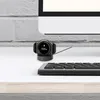 A smartwatch is charging on its dock next to a keyboard, with a computer monitor in the background. Náhľad obrázku produktu