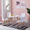 A white round dining table with four white chairs in a room with pink walls and a window. Voir les images du produit
