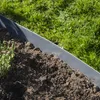 A close-up view of a garden border made of galvanized steel, separating soil from grass. Produktbild-Vorschau
