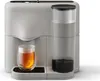 A gray and black electric tea maker with a glass of tea next to it. Produktbild-Vorschau