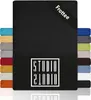 A black fitted sheet is shown with a stack of other colored fitted sheets on the left and right sides. The brand logo is visible on the front of the sheet. Produktbild-Vorschau