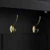 A close-up view of two gold hooks mounted on a black surface. Podgląd zdjęcia produktu