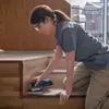 A woman is sanding wooden stairs with a power tool. Anteprima dell’immagine prodotto