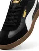 A close-up view of a black Puma shoe with a white stripe and gold branding. Voir les images du produit