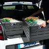 A person is loading two black storage crates filled with water bottles and bread into the trunk of a car. Produktbild-Vorschau