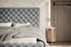 A close-up view of a tufted headboard and bedding in a bedroom setting. Náhľad obrázku produktu