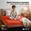 A young boy sitting on a bed with an orange fitted sheet. Produktbild-Vorschau