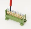 A close-up shot of a green terminal block with brass connectors and screws, with a screwdriver tip inserted into one of the screws. Produktbild-Vorschau